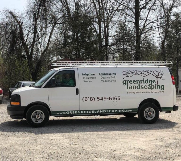 A white van featuring the "Greenridge Landscaping" logo and contact info is parked on gravel, strategically equipped with vehicle tracking for landscapers. Tree branches sway gently in the background, completing the serene scene.