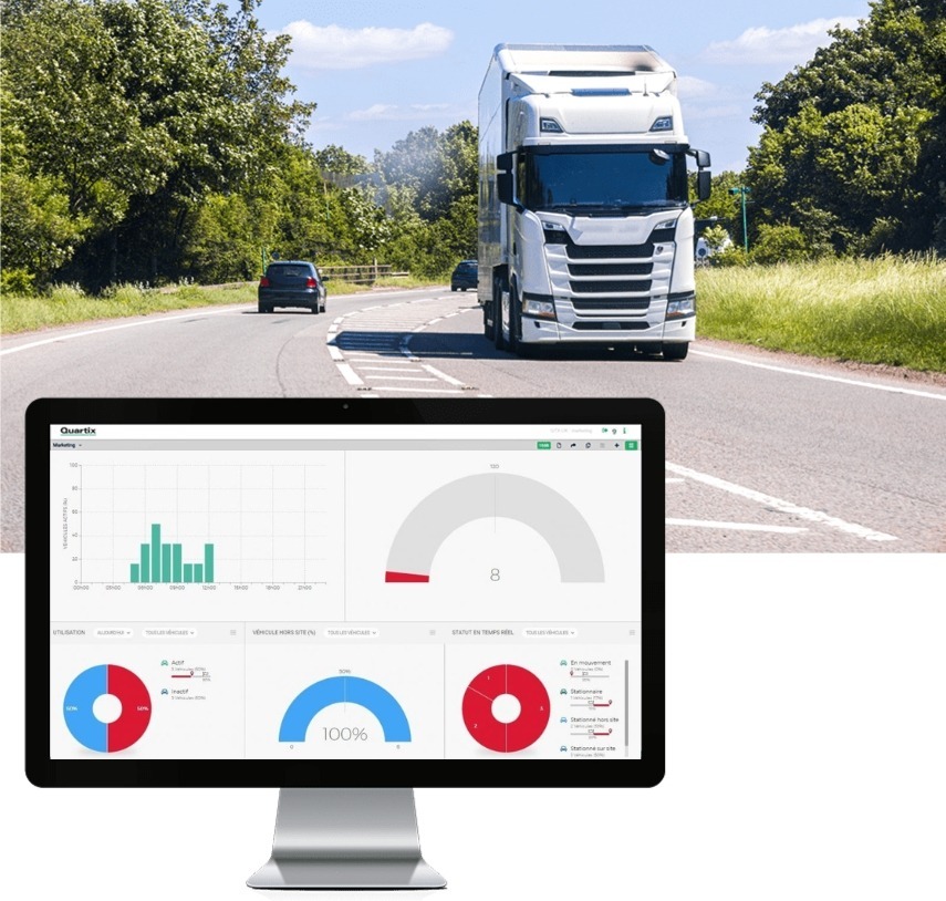 Un écran d'ordinateur affichant des graphiques d'analyse de flotte de véhicules est montré devant une scène de route avec un grand camion et des voitures, mettant en évidence un suivi efficace des véhicules de livraison pendant la journée.