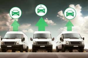 Three white vans are parked in a row with green arrows and car icons above them, suggesting a transition or upgrade to electric vehicles.