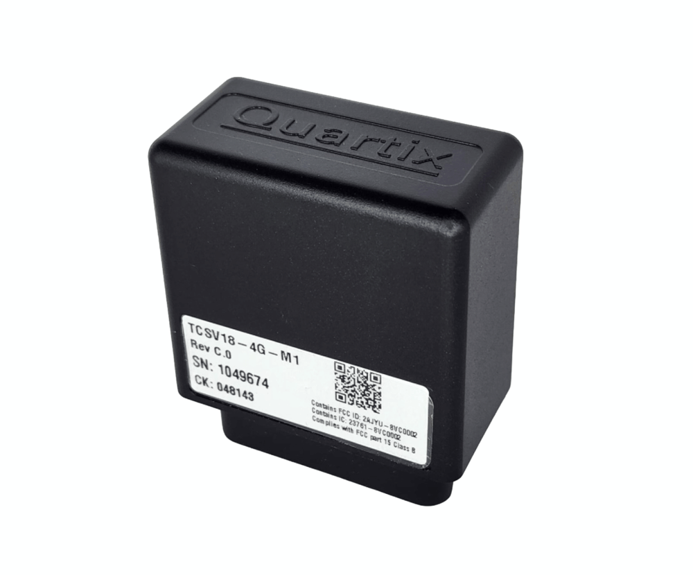 A black Quartix plug and track OBD device with a labeled sticker showing model, serial number, and QR code on a white background.
