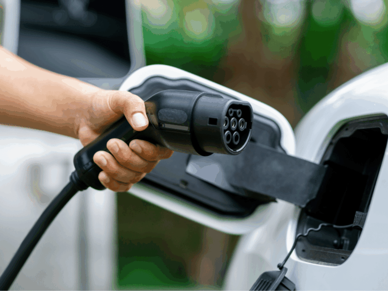 A hand plugging an electric vehicle charging connector into a car port as you consider if your fleet is ready for EVs.